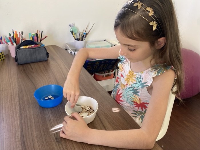 Une enfant manipule de petits objets pour travailler la motricité fine