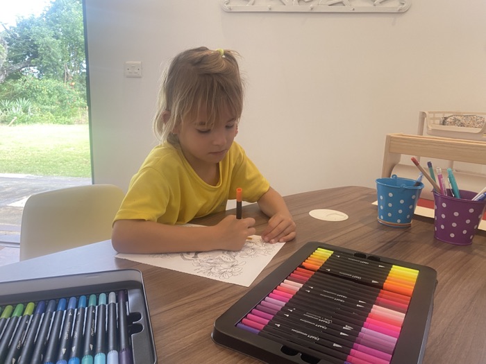 Une enfant colorie avec des feutres