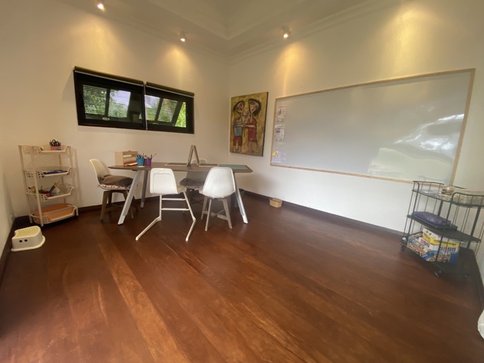 Vue d'ensemble de l'atelier : grande table, chaises blanches et tableau blanc